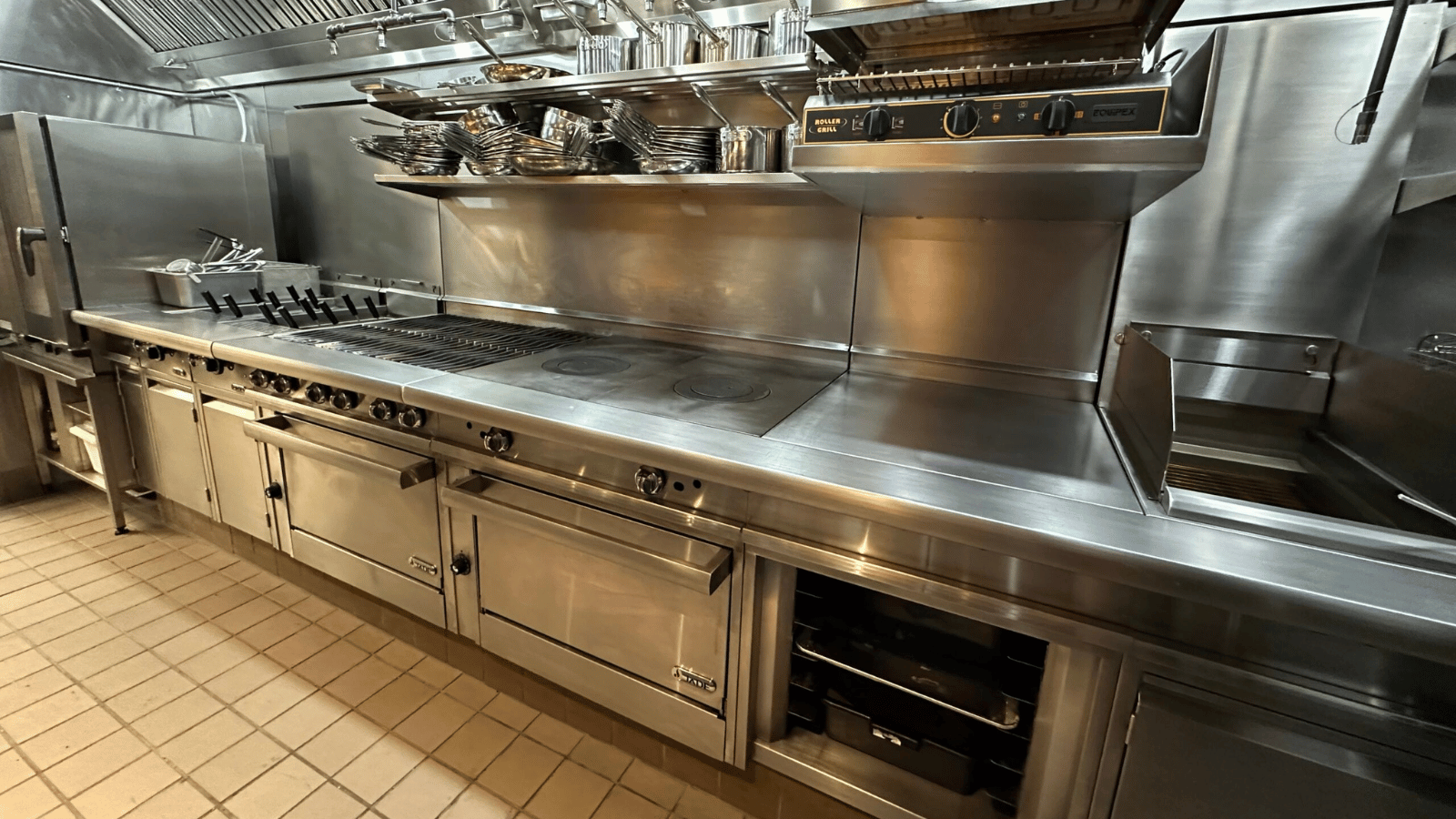 Suite of stainless steel ovens, ranges and grills from Jade Range again a wall in commercial kitchen. 